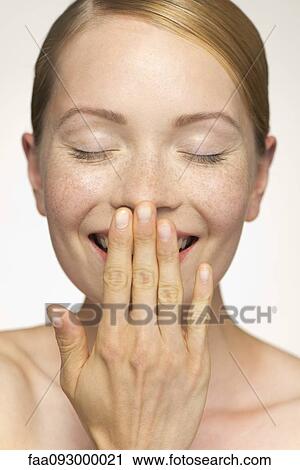 Young woman smiling, covering mouth with hand View Large Photo Image Stock Image - Young woman smiling, covering mouth with hand. Fotosearch