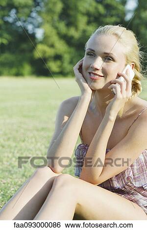 Stock Photograph - Young woman talking on cell phone outdoors. Fotosearch