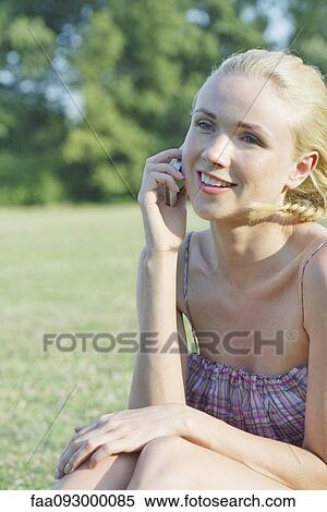 Stock Photography - Young woman talking on cell phone outdoors. Fotosearch