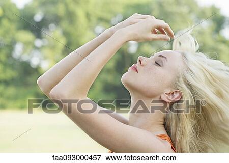 Young woman tossing her hair outdoors, portrait View Large Photo Image Stock Photo - Young woman tossing her hair outdoors, portrait. Fotosearch