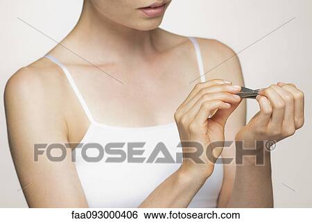 Stock Photograph - Young woman trimming fingernails. Fotosearch