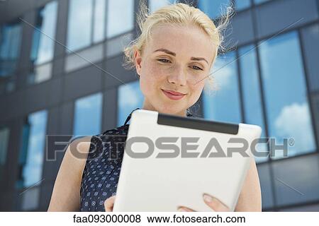 Stock Photo - Young woman using digital tablet outdoors. Fotosearch