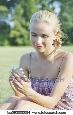 Young woman using smartphone outdoors View Large Photo Image Picture - Young woman using smartphone outdoors. Fotosearch