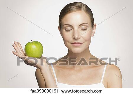 Young woman with eyes closed holding green apple View Large Photo Image Stock Image - Young woman with eyes closed holding green apple. Fotosearch