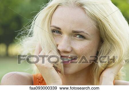 Stock Photo - Young woman with hands in hair, smiling, portrait. Fotosearch