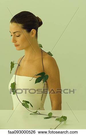 Stock Photograph - Young woman with leafy vine hanging around shoulders, eyes closed. Fotosearch