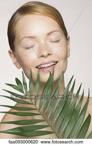 Stock Image - Young woman with palm frond. Fotosearch