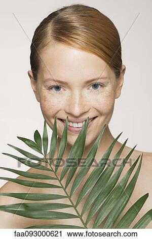 Stock Image - Young woman with palm frond. Fotosearch