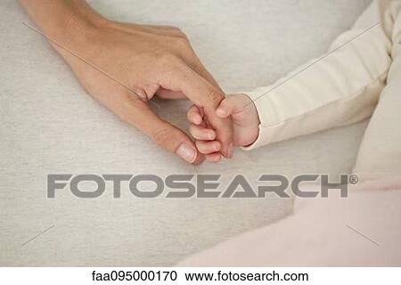 Stock Image - Baby holding mother's hand, cropped. Fotosearch