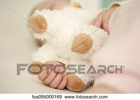 Stock Photo - Baby holding stuffed toy, selective focus. Fotosearch