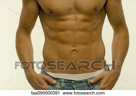 Stock Image - Barechested man with hands in pockets, mid section. Fotosearch