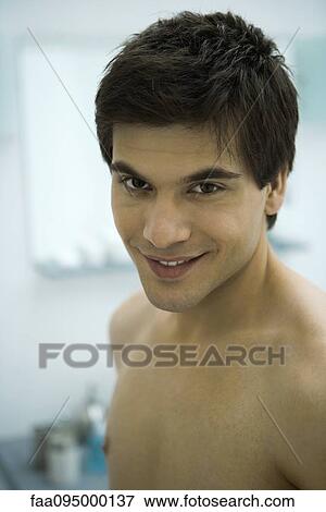 Stock Photo - Barechested young man smiling at camera, portrait. Fotosearch