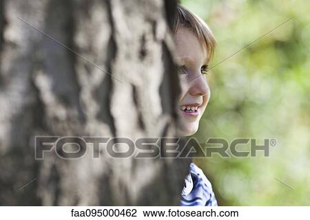 Stock Image - Boy behind tree. Fotosearch