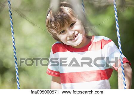 Stock Image - Boy on swing, portrait. Fotosearch