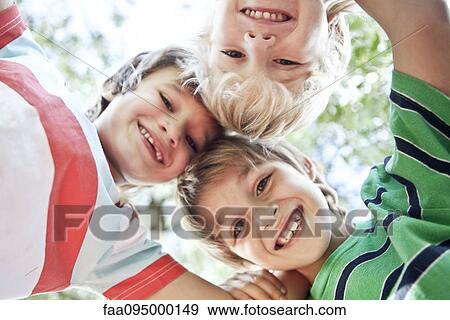 Stock Photo - Boys huddling, smiling down at camera. Fotosearch