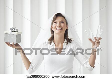 Stock Image - Bride holding champagne flutes and gift box. Fotosearch