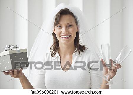 Bride holding champagne flutes and gift box View Large Photo Image Stock Image - Bride holding champagne flutes and gift box. Fotosearch