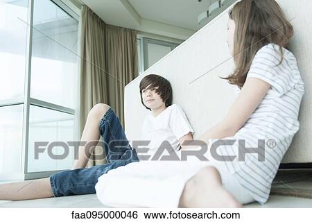 Brother and sister sitting on floor, leaning against back of sofa View Large Photo Image Stock Photograph - Brother and sister sitting on floor, leaning against back of sofa. Fotosearch
