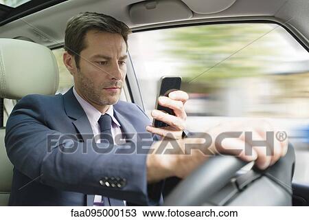 Businessman looking at smartphone in car View Large Photo Image Stock Image - Businessman looking at smartphone in car. Fotosearch