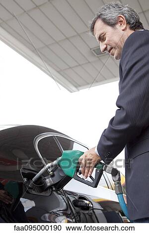 Businessman refueling car at gas station View Large Photo Image Stock Image - Businessman refueling car at gas station. Fotosearch