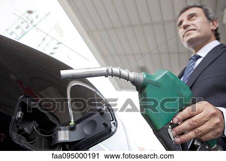 Businessman refueling car at gas station View Large Photo Image Stock Image - Businessman refueling car at gas station. Fotosearch