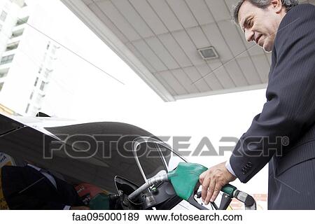 Businessman refueling car at gas station View Large Photo Image Stock Photo - Businessman refueling car at gas station. Fotosearch