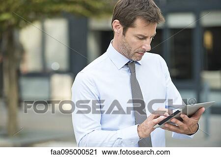 Businessman using digital tablet outdoors View Large Photo Image Stock Image - Businessman using digital tablet outdoors. Fotosearch