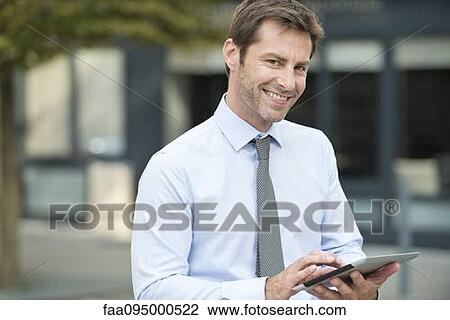 Stock Image - Businessman using digital tablet outdoors. Fotosearch