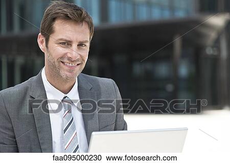 Businessman using laptop outdoors View Large Photo Image Stock Image - Businessman using laptop outdoors. Fotosearch