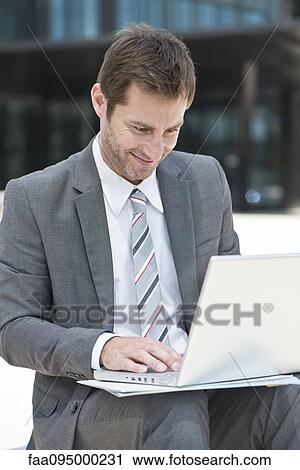 Businessman using laptop outdoors View Large Photo Image Stock Image - Businessman using laptop outdoors. Fotosearch