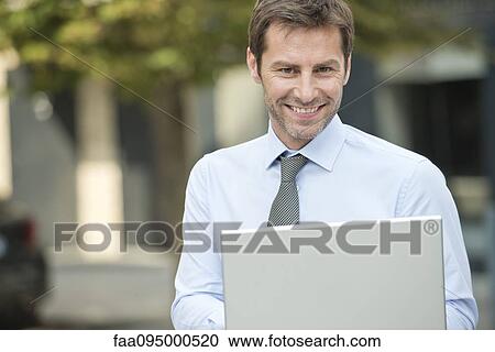 Stock Image - Businessman using laptop outdoors. Fotosearch