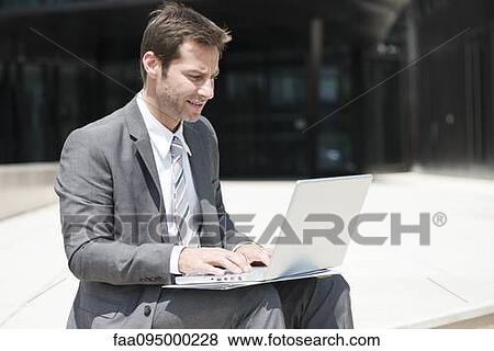 Stock Photo - Businessman using laptop outdoors. Fotosearch