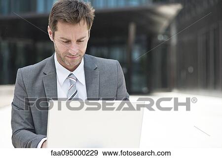 Businessman using laptop outdoors View Large Photo Image Stock Photo - Businessman using laptop outdoors. Fotosearch