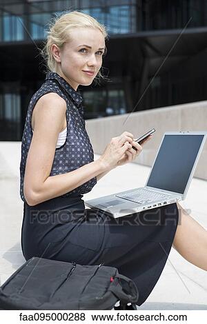 Businesswoman using laptop and smartphone working outdoors View Large Photo Image Stock Photo - Businesswoman using laptop and smartphone working outdoors. Fotosearch
