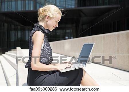 Stock Photograph - Businesswoman using laptop working outdoors. Fotosearch