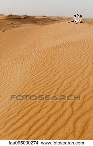 Picture - Children sitting on sand dune. Fotosearch