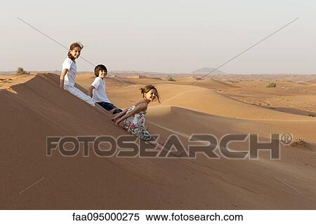 Stock Photography - Children sitting on sand dune. Fotosearch