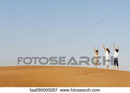 Children standing in desert with arms raised in air View Large Photo Image Stock Photo - Children standing in desert with arms raised in air. Fotosearch