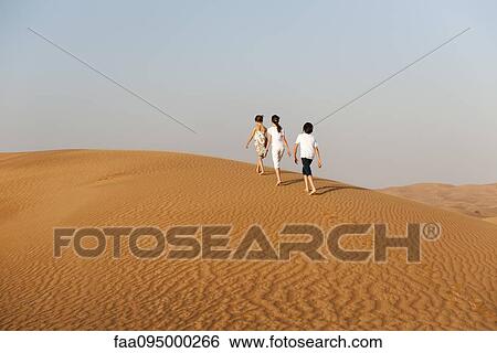 Stock Photograph - Children walking in desert, rear view. Fotosearch
