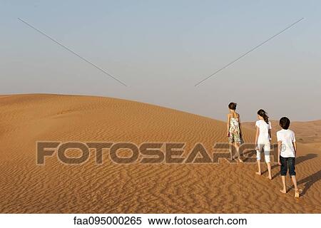 Stock Photography - Children walking in desert, rear view. Fotosearch