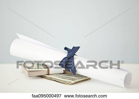 College diploma set atop stacks of cash View Large Photo Image Stock Photo - College diploma set atop stacks of cash. Fotosearch