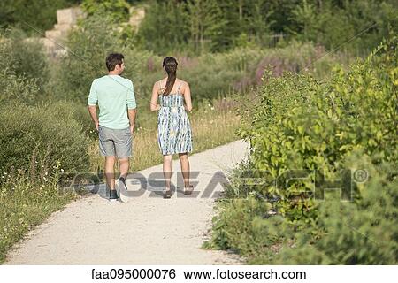 Stock Photograph - Couple together on walk through park, rear view. Fotosearch