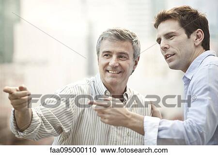 Stock Image - Friends hanging out, pointing into distance. Fotosearch