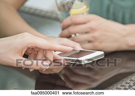 Stock Image - Friends looking at smartphone together. Fotosearch