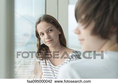 Stock Image - Girl leaning against window, daydreaming. Fotosearch
