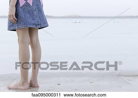 Girl standing at water's edge at the beach, low section View Large Photo Image Stock Image - Girl standing at water's edge at the beach, low section. Fotosearch