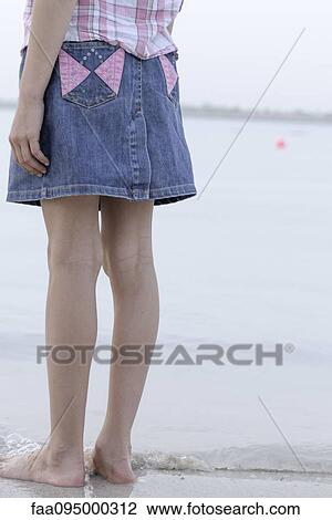 Girl standing at water's edge at the beach, low section View Large Photo Image Stock Image - Girl standing at water's edge at the beach, low section. Fotosearch