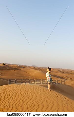 Girl standing in desert with arms raised in air View Large Photo Image Stock Photo - Girl standing in desert with arms raised in air. Fotosearch