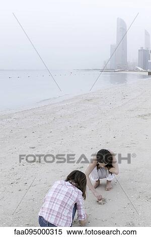 Stock Photography - Girls looking for seashells at the beach. Fotosearch