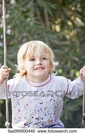 Stock Image - Little boy playing on swing. Fotosearch